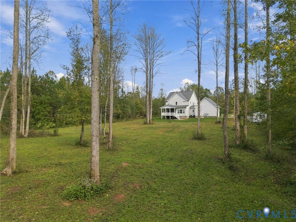 Expansive wooded acreage featuring a grassy clearing and a residence with a covered rear porch and gable roofline