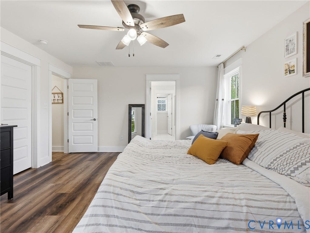 Wood-finish flooring, multi-panel interior doors, and a ceiling fan with integrated lighting