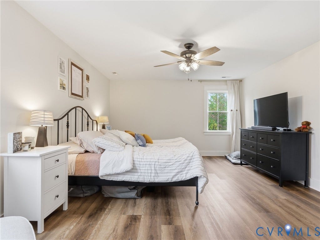 Room with wood-finish flooring, multi-pane window, and integrated ceiling fan with light fixture