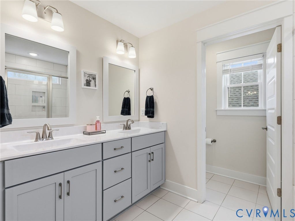 Double vanity featuring gray Shaker-style cabinetry, white countertops, rectangular undermount sinks, and dual-light wall sconces with white glass shades