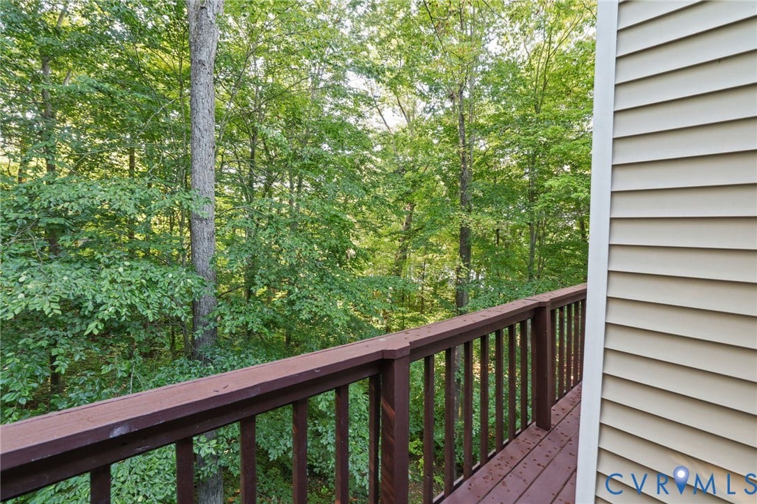 4815 Woodbriar Court, Midlothian, VA 23112 Elevated wood-tone deck with vertical balustrade, beige horizontal siding, and dense woodland scenery