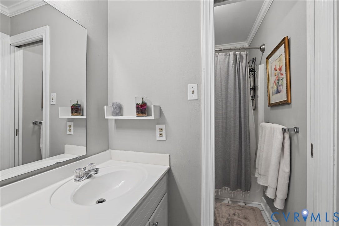 4815 Woodbriar Court, Midlothian, VA 23112 Bathroom featuring a white vanity with an integrated basin, a large wall-mounted mirror, built-in shelving, and a tiled shower area