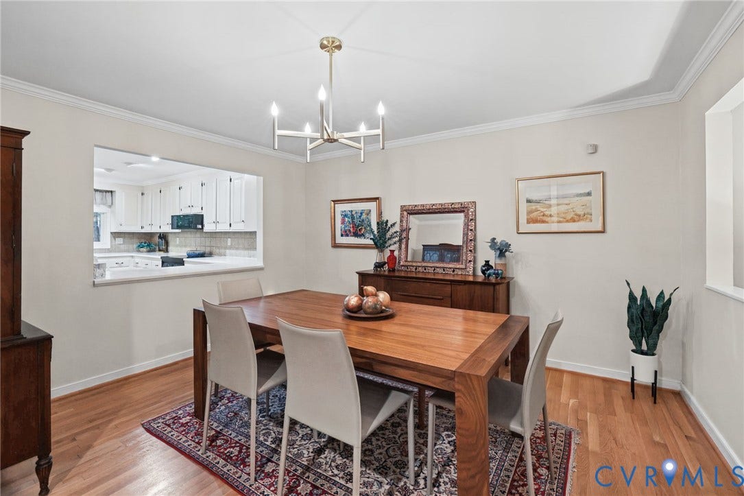 4815 Woodbriar Court, Midlothian, VA 23112 Dining room featuring wood-finish flooring, a tiered candle-style chandelier, tray ceiling, crown molding, and a pass-through window