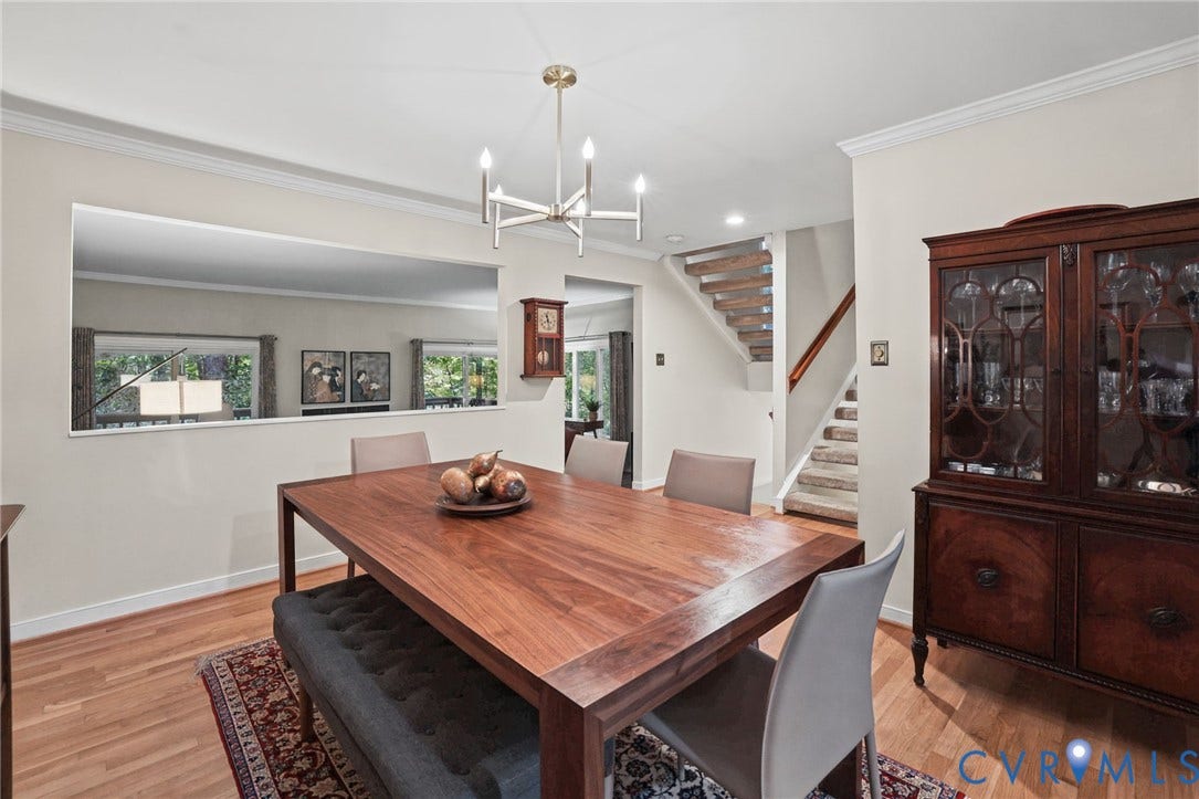 4815 Woodbriar Court, Midlothian, VA 23112 Dining area featuring wood-finish flooring, a modern multi-arm chandelier, an architectural wall cutout, and a staircase with an open-riser design