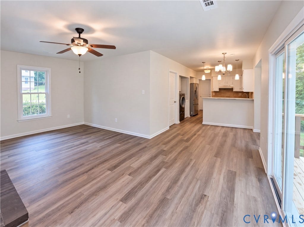 Open-concept layout featuring wood-finish flooring, a ceiling fan, and sliding glass doors to an exterior deck
