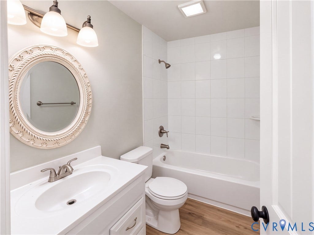 White vanity with integrated sink, brushed nickel faucet, and wood-finish flooring