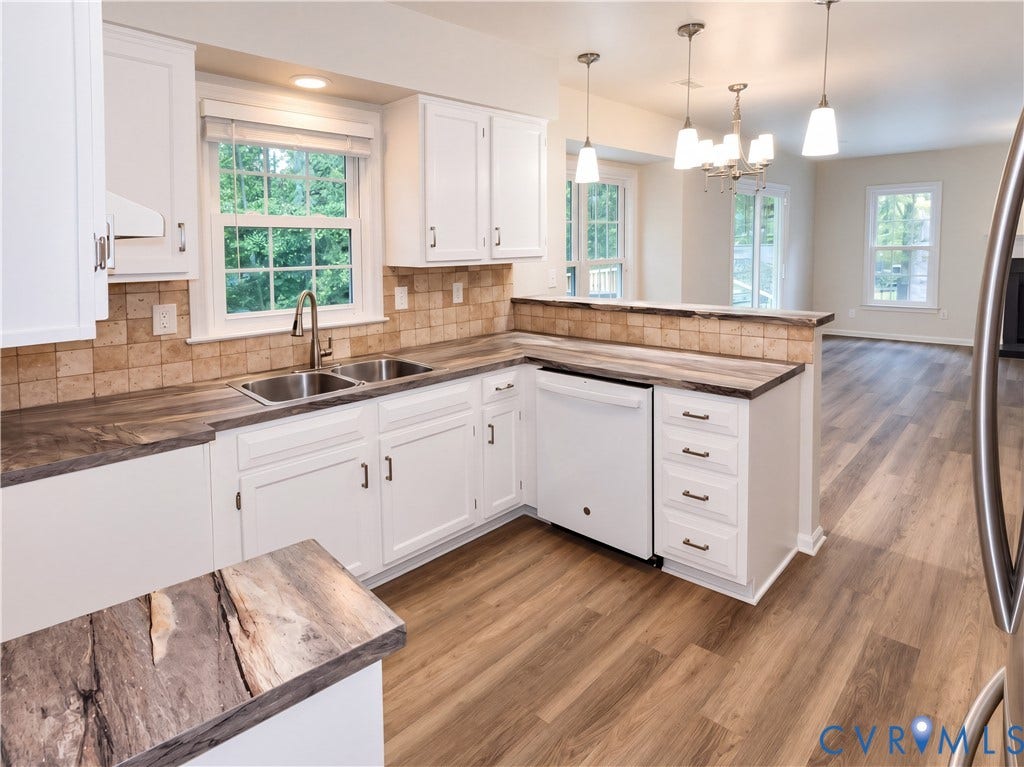 White cabinetry with dark hardware, stone-finish countertops, and a tiled backsplash