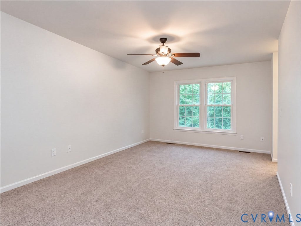Neutral wall paint, carpeted flooring, double window, and ceiling fan with integrated lighting