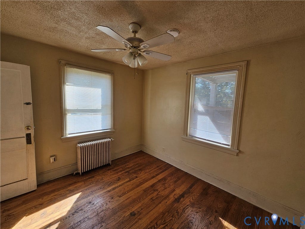 613 E Brookland Park Boulevard, #2, Richmond, VA 23222 Wood-finish flooring with a ceiling fan light fixture and two windows with blinds