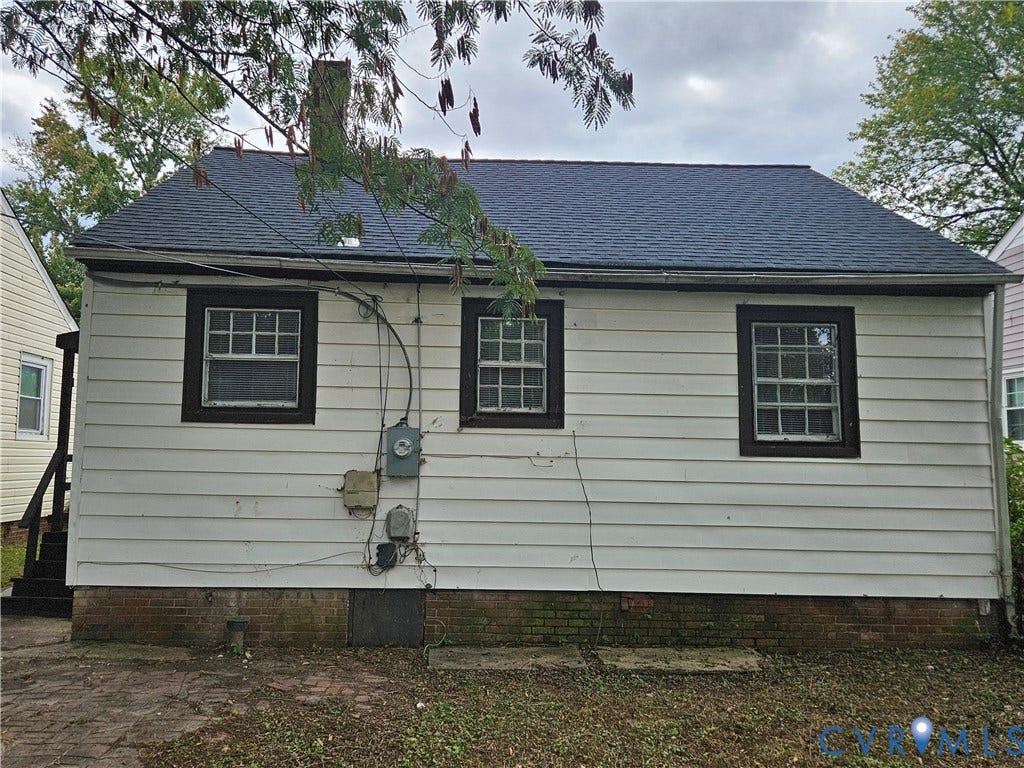 1410 E 18th Street, Richmond, VA 23224 White horizontal siding exterior with a dark shingle roof, dark window trim, and a brick foundation