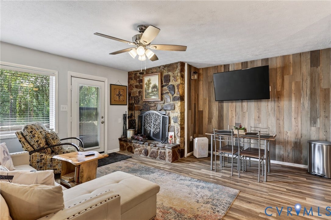 1836 FAIRWAY Drive, #218, Aspen East, Basye, VA 22810 Stone fireplace with a decorative screen, wood-finish flooring, accent wall with vertical wood paneling, ceiling fan with integrated lighting, and multiple windows