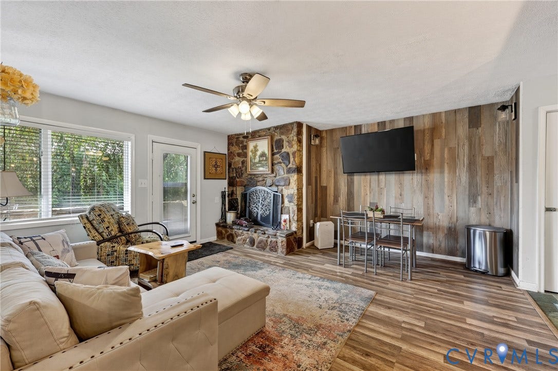 1836 FAIRWAY Drive, #218, Aspen East, Basye, VA 22810 Spacious living area featuring wood-finish flooring, a stone fireplace, a wood-paneled accent wall, and multiple windows