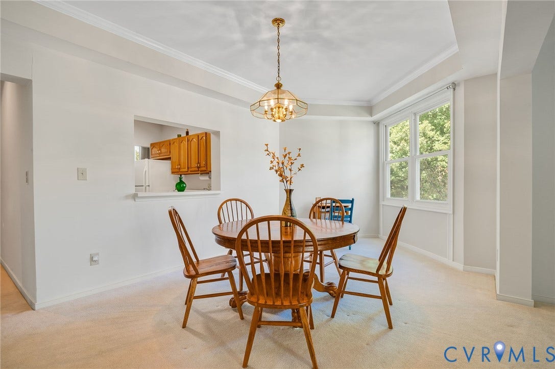 Dining area featuring crown molding, a decorative multi-arm pendant light fixture, and a pass-through window looking toward built-in cabinetry