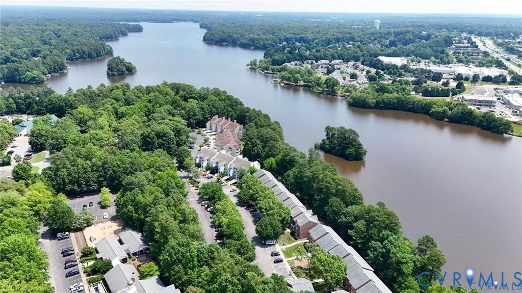 Aerial perspective of residential structures featuring brick facades, shingled roofing, paved parking areas, and waterfront access