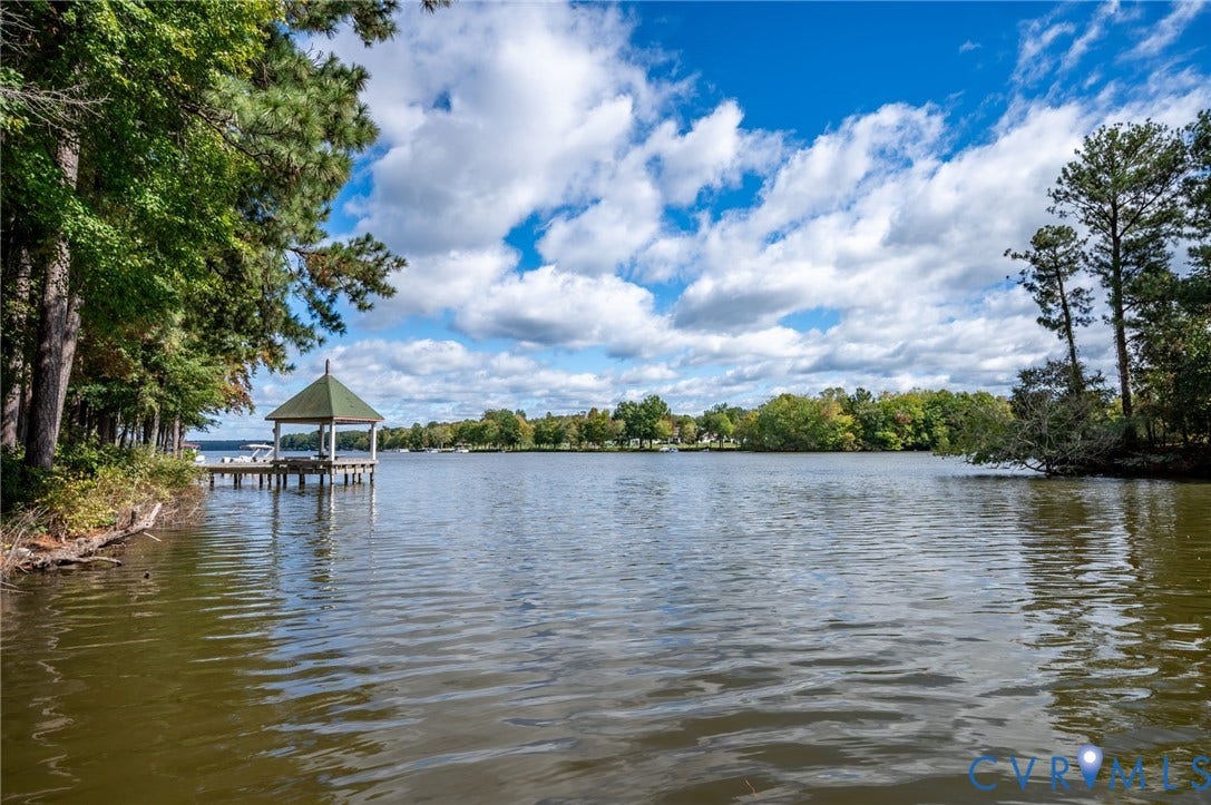 Waterfront lot featuring a covered stationary dock and mature shoreline tree canopy