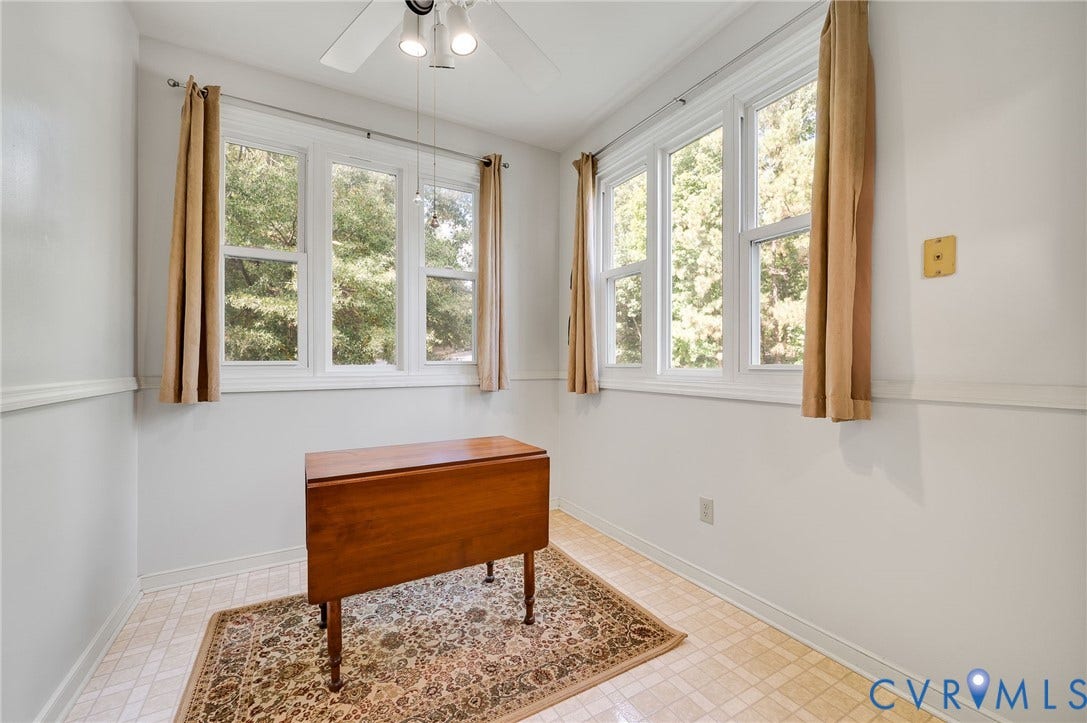 Neutral-toned room featuring light-colored tile flooring, white walls with chair rail molding, multi-pane windows, and a ceiling-mounted light fixture
