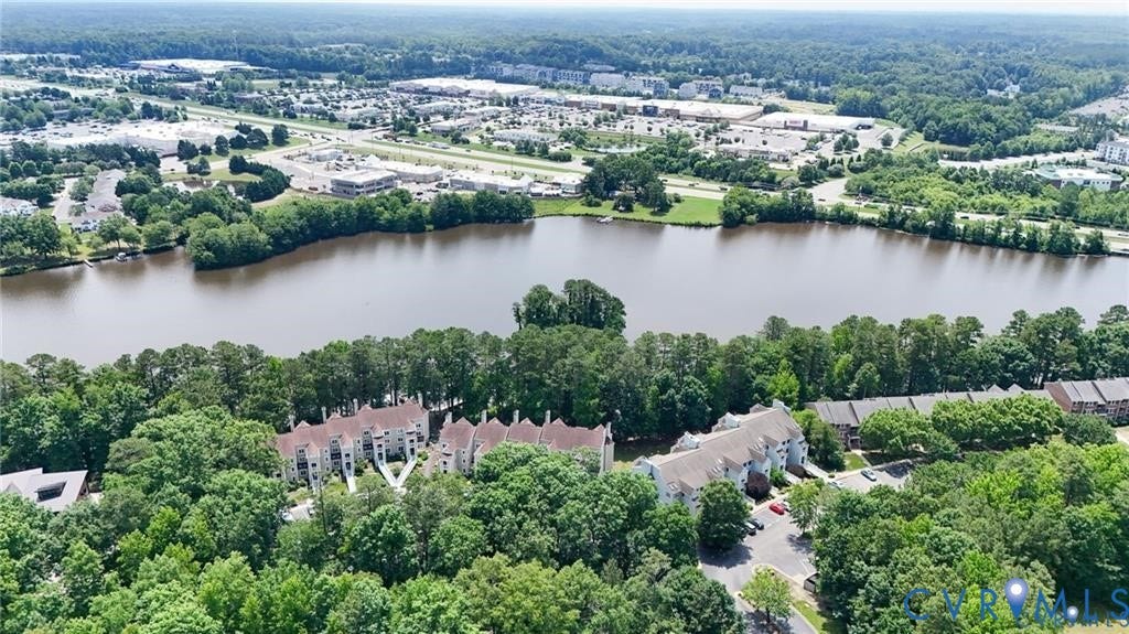 Aerial perspective featuring multi-story residential structures situated on a shoreline with surrounding mature trees and woodland areas