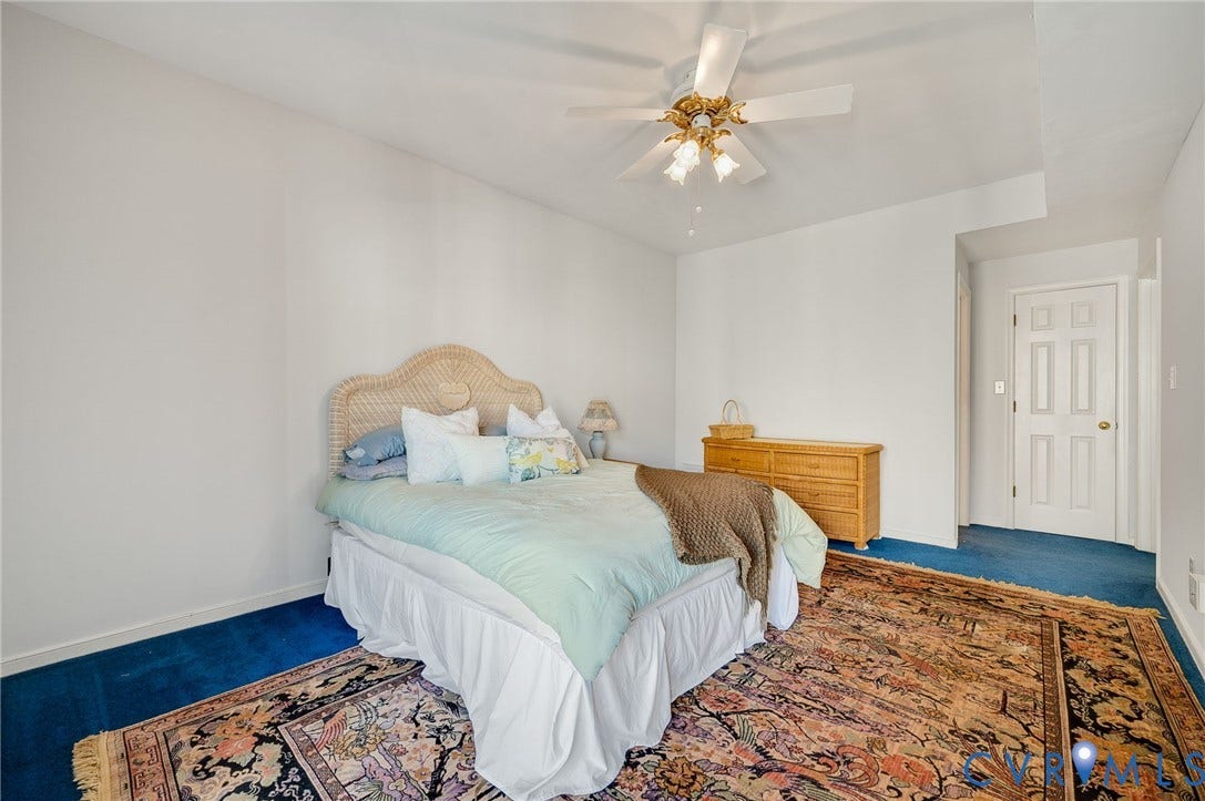 Room featuring high ceilings, white wall finishes, and a four-blade ceiling fan with integrated light fixture, complemented by a six-panel interior door