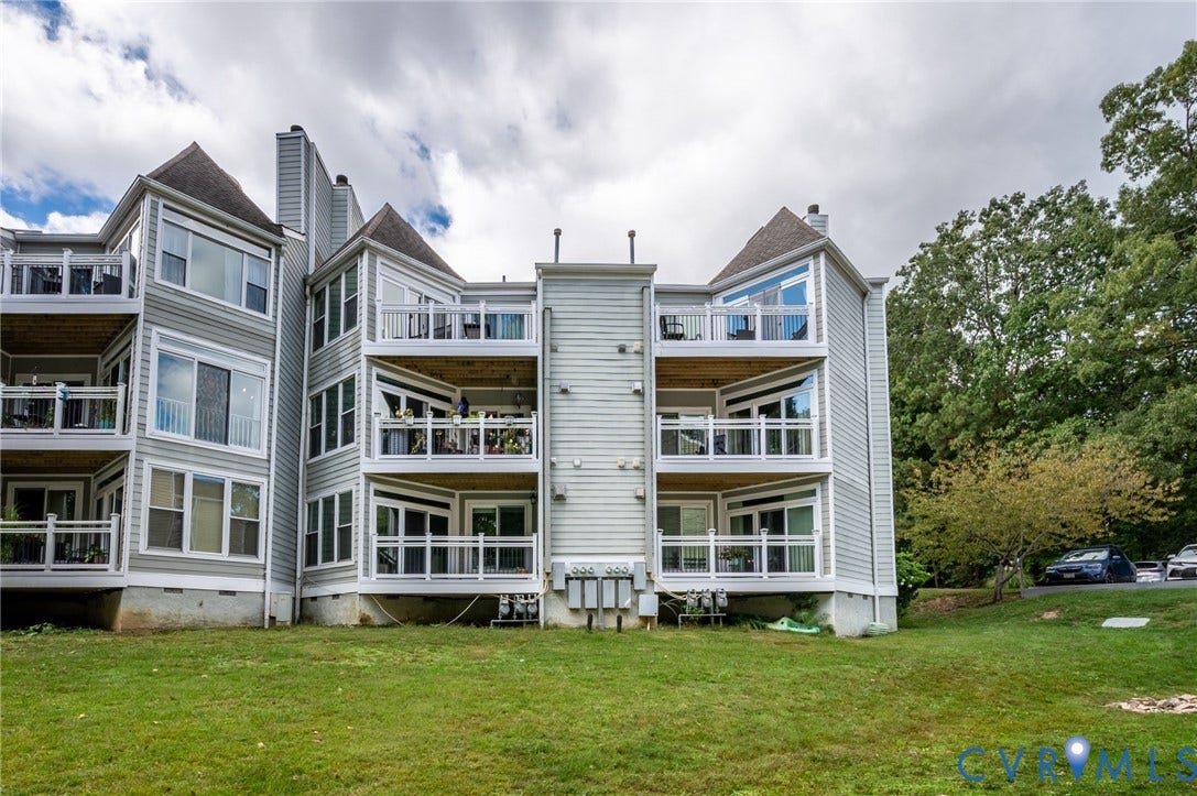 Multi-level exterior featuring light-toned horizontal siding, tiered balconies with white railings, and peaked roof accents