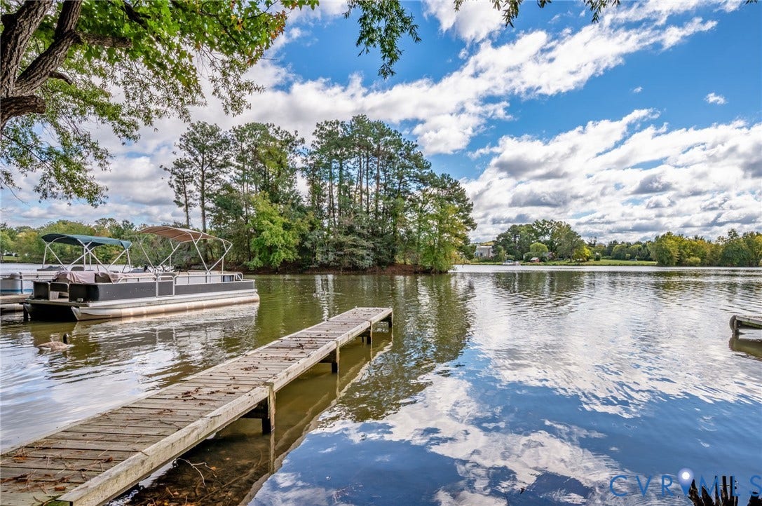 Waterfront property featuring a wood-plank dock, expansive lake frontage, and mature tree-lined shoreline