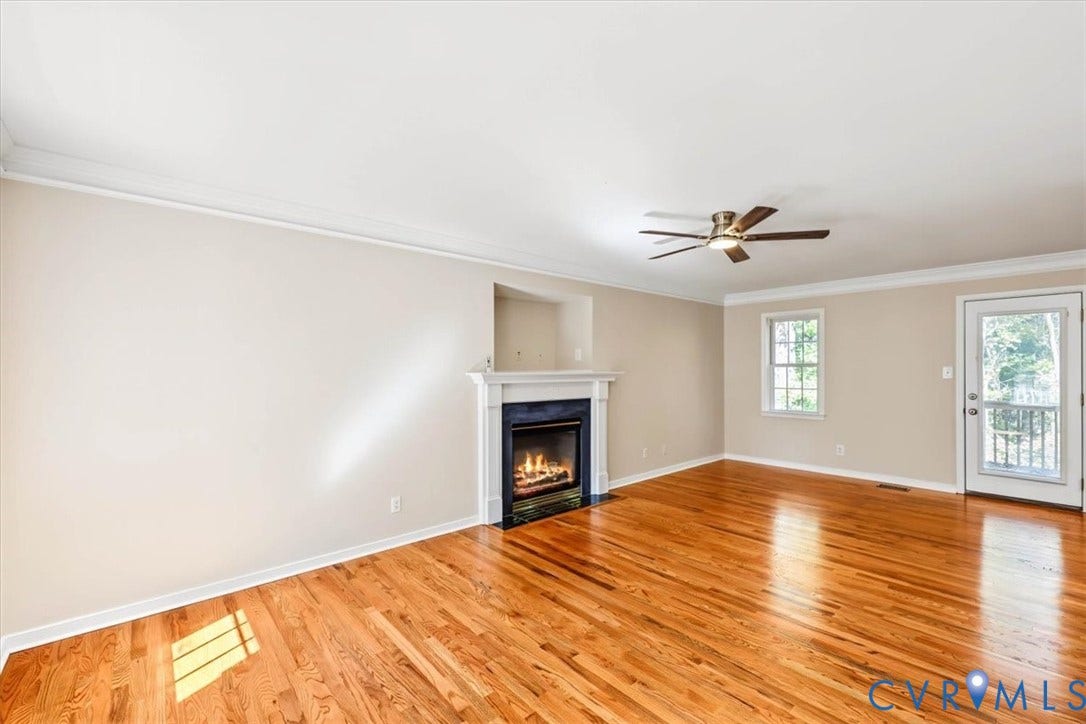 3216 Sherwood Bluff Terrace, Sherwood Bluff, Powhatan, VA 23139 Living area featuring wood-finish flooring, a fireplace with a white mantel, crown molding, a ceiling fan, and a glass-paneled exterior door