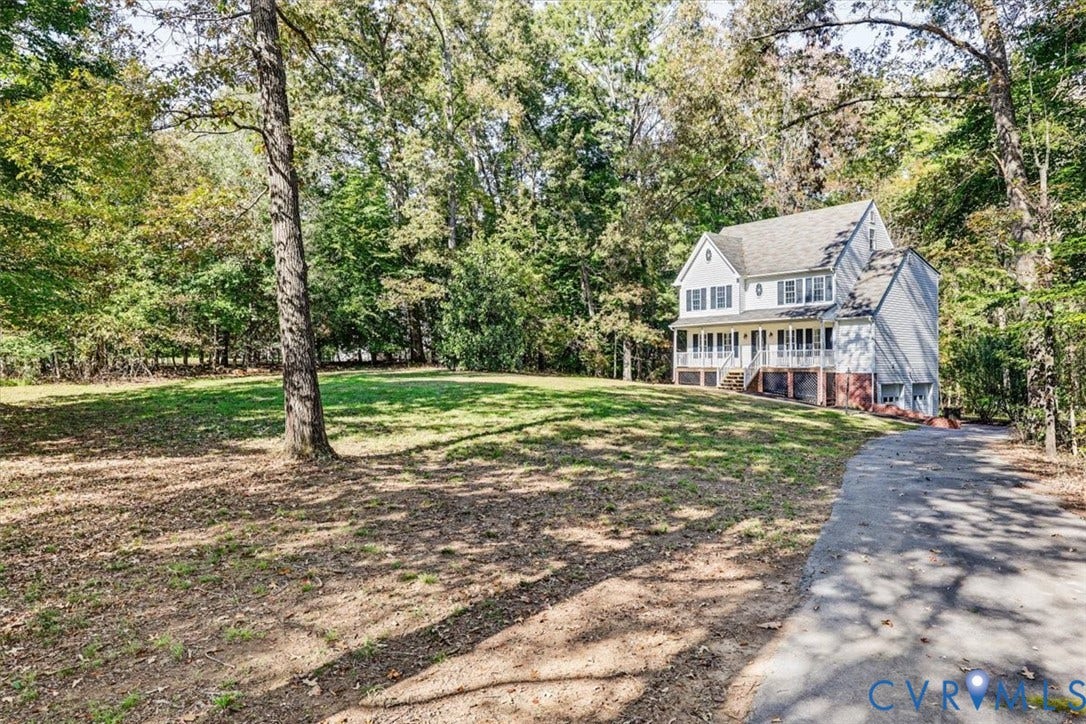 3216 Sherwood Bluff Terrace, Sherwood Bluff, Powhatan, VA 23139 Two-story residence featuring a brick and siding facade, covered front porch, asphalt driveway, and expansive lawn area surrounded by mature trees