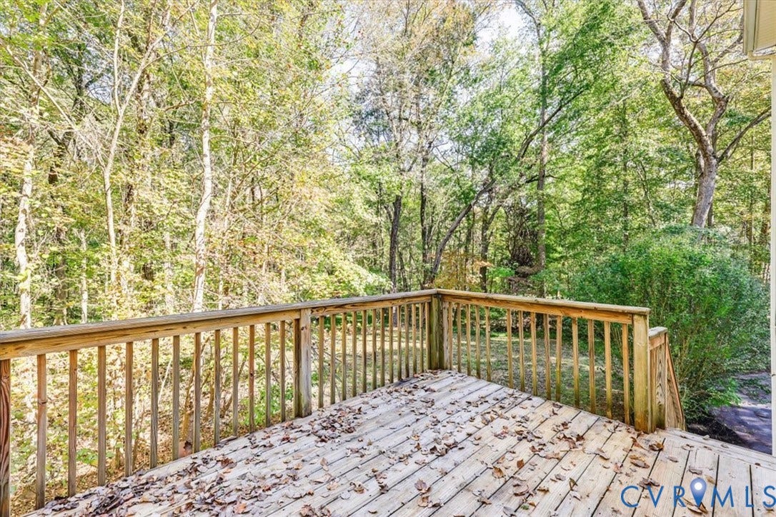 3216 Sherwood Bluff Terrace, Sherwood Bluff, Powhatan, VA 23139 Raised wood deck featuring vertical wood balusters and a wood railing, situated among mature trees