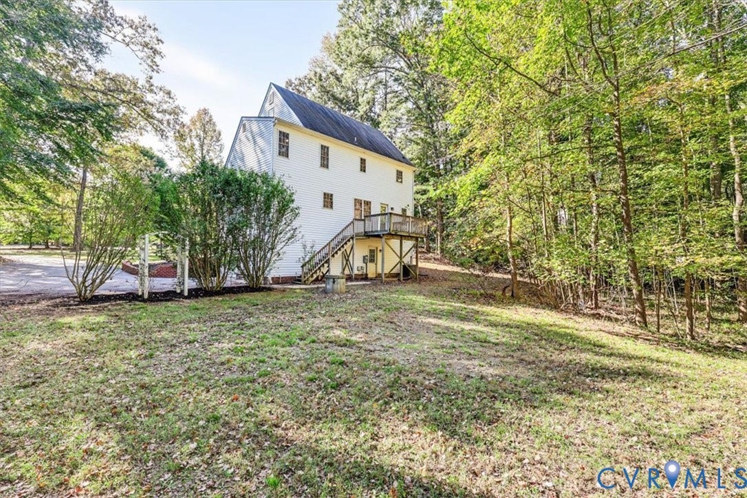 3216 Sherwood Bluff Terrace, Sherwood Bluff, Powhatan, VA 23139 Two-story residence featuring a wood-siding exterior, elevated wood deck with stairs, and expansive grounds surrounded by mature trees