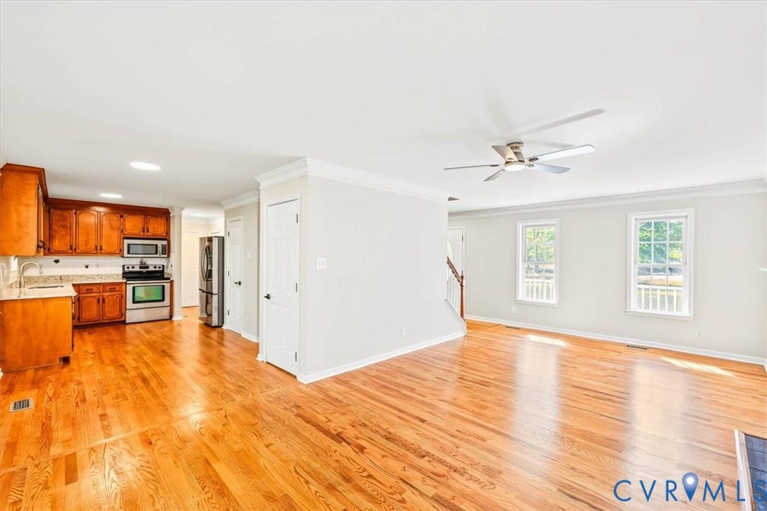 3216 Sherwood Bluff Terrace, Sherwood Bluff, Powhatan, VA 23139 Open-concept interior featuring wood-finish flooring, crown molding, a ceiling fan, and a kitchen equipped with wood cabinetry and stainless steel appliances