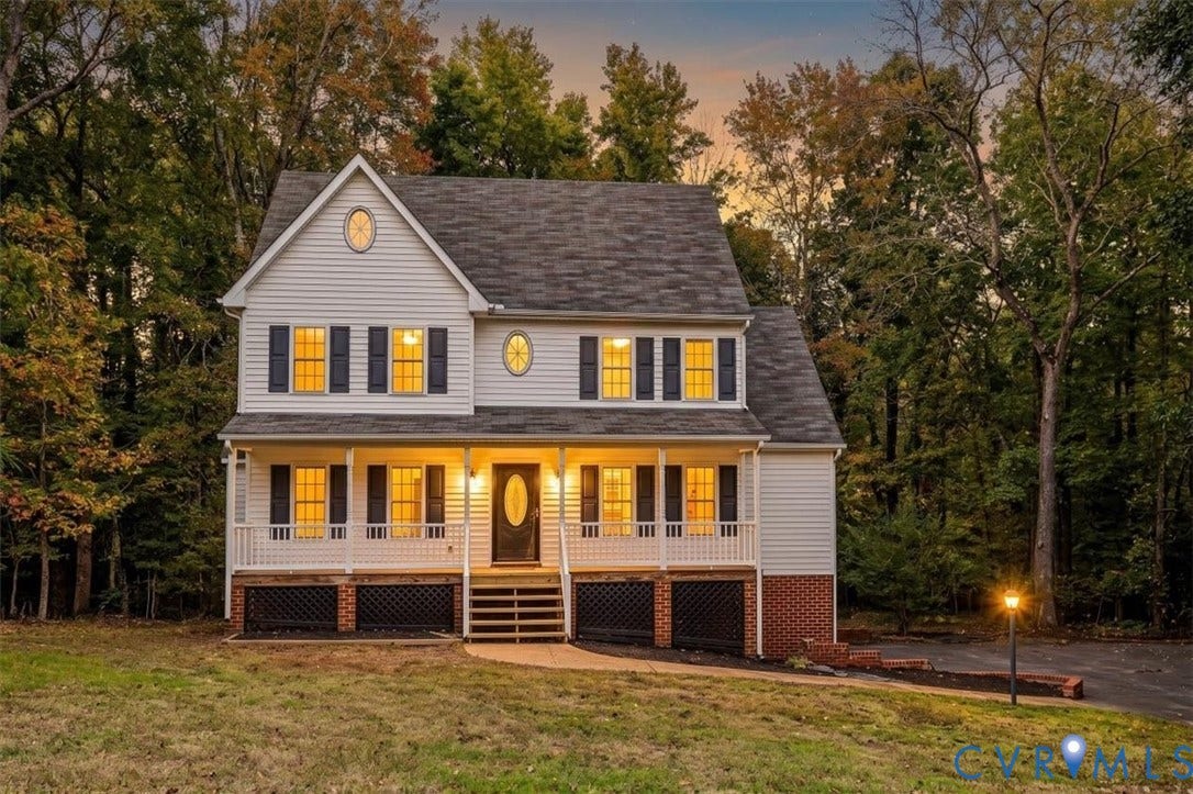 3216 Sherwood Bluff Terrace, Sherwood Bluff, Powhatan, VA 23139 Two-story residence featuring horizontal lap siding, a covered front porch with balustrade railings, decorative oval windows, asphalt shingle roofing, and a brick-faced foundation