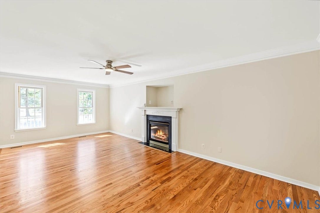 3216 Sherwood Bluff Terrace, Sherwood Bluff, Powhatan, VA 23139 Spacious room featuring wood-finish flooring, a fireplace with a white mantel, crown molding, and a ceiling fan