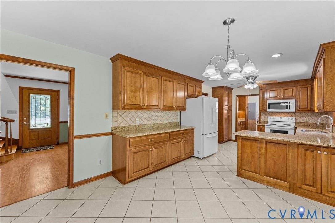 11612 Yorkdale Drive, Rivers Edge, North Prince George, VA 23860 Spacious kitchen featuring warm wood cabinetry, white appliances, tile countertops, decorative tile backsplash, and a pendant light fixture