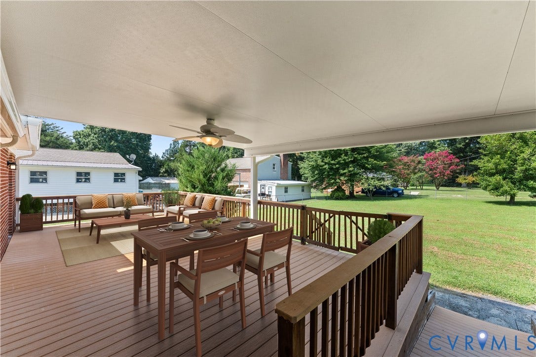 11612 Yorkdale Drive, Rivers Edge, North Prince George, VA 23860 Expansive deck featuring multiple entertaining zones with wood-finish decking, a ceiling fan for year-round comfort, and a dining table area overlooking manicured lawn and mature landscaping