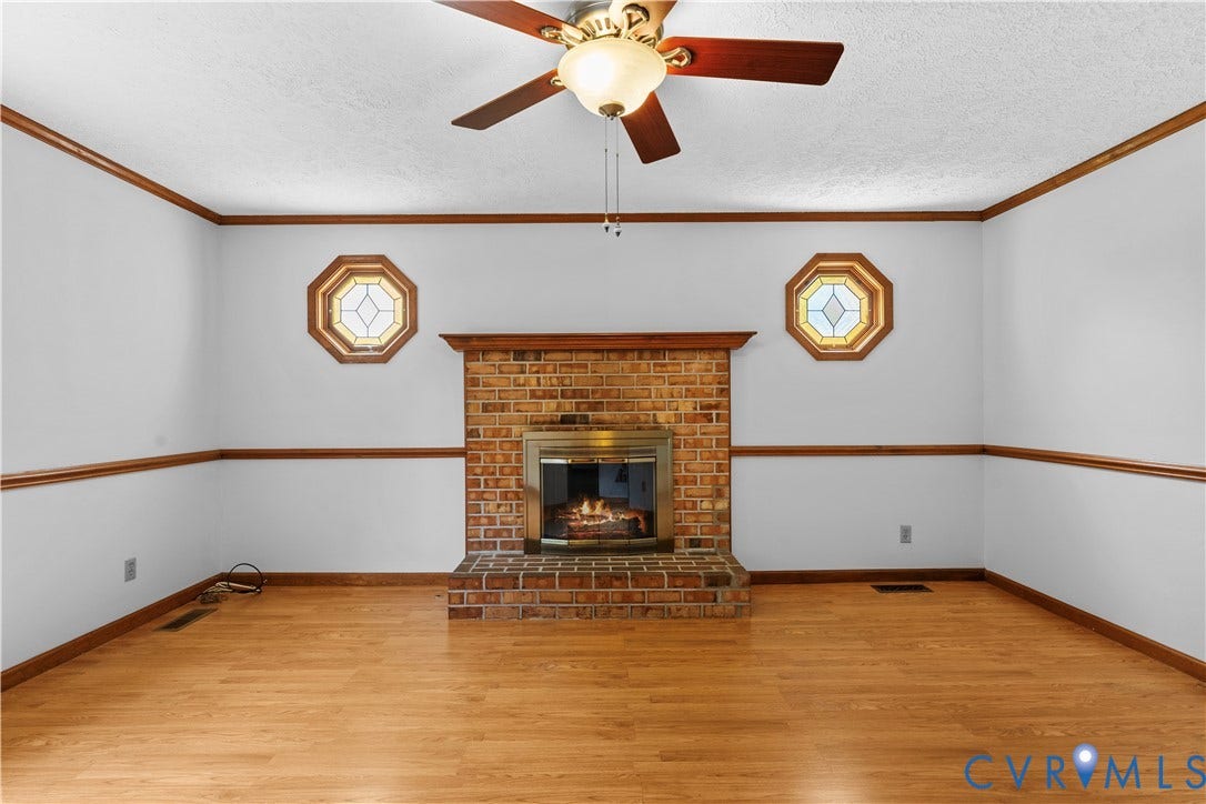 11612 Yorkdale Drive, Rivers Edge, North Prince George, VA 23860 Brick fireplace with a brass-finish insert, wood-finish flooring, and two octagonal decorative windows