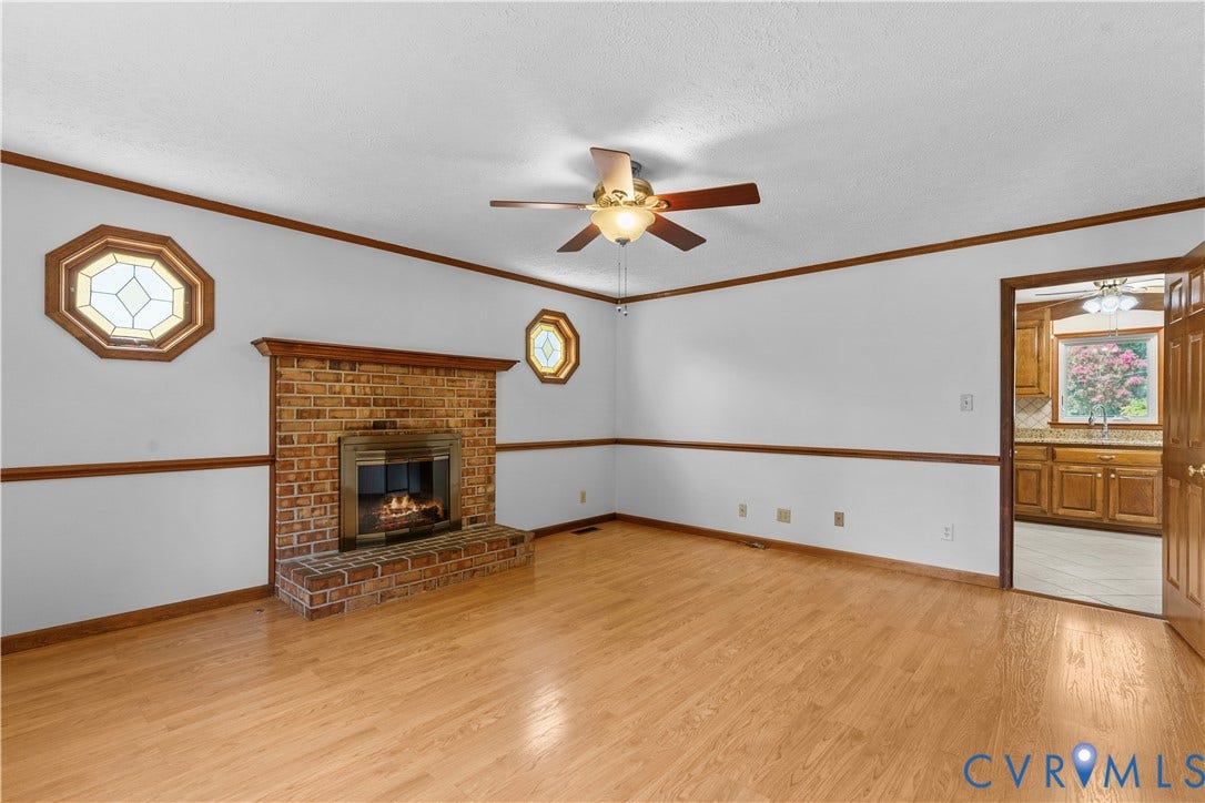 11612 Yorkdale Drive, Rivers Edge, North Prince George, VA 23860 Brick-surround fireplace with a wood mantle, two octagonal windows, wood-finish flooring, and a ceiling fan