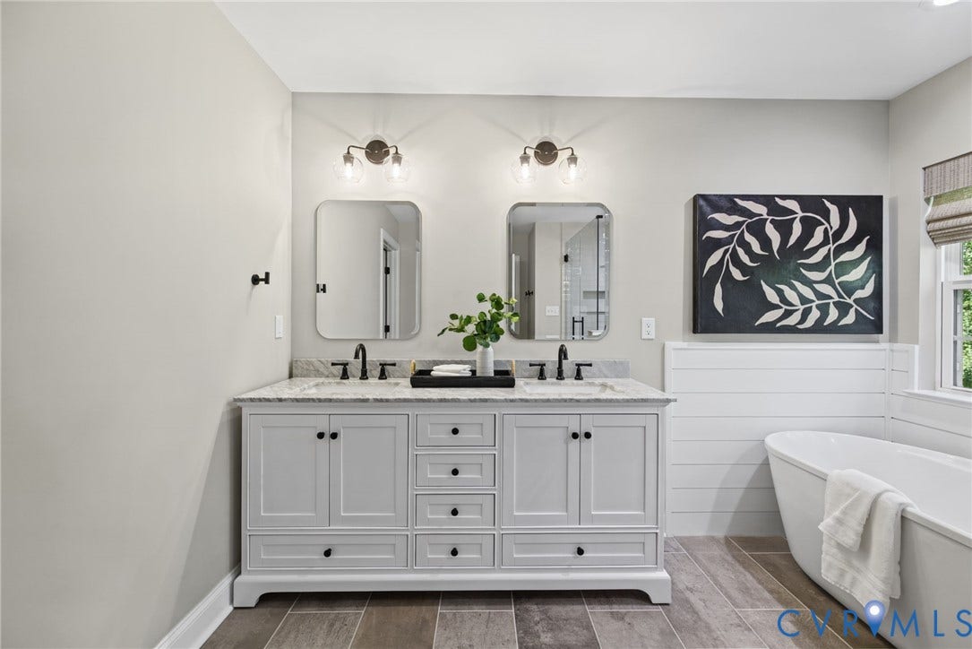1425 Montcroft Way, Midlothian, VA 23112 Double vanity featuring a stone countertop, dual undermount sinks with matte black faucets, rectangular wall-mounted mirrors, two-tone cabinetry, and a freestanding soaking tub with shiplap wainscoting