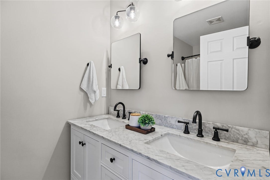 1425 Montcroft Way, Midlothian, VA 23112 Dual-sink vanity with stone countertop, white shaker-style cabinetry, matte black widespread faucets, and twin rectangular mirrors with rounded corners