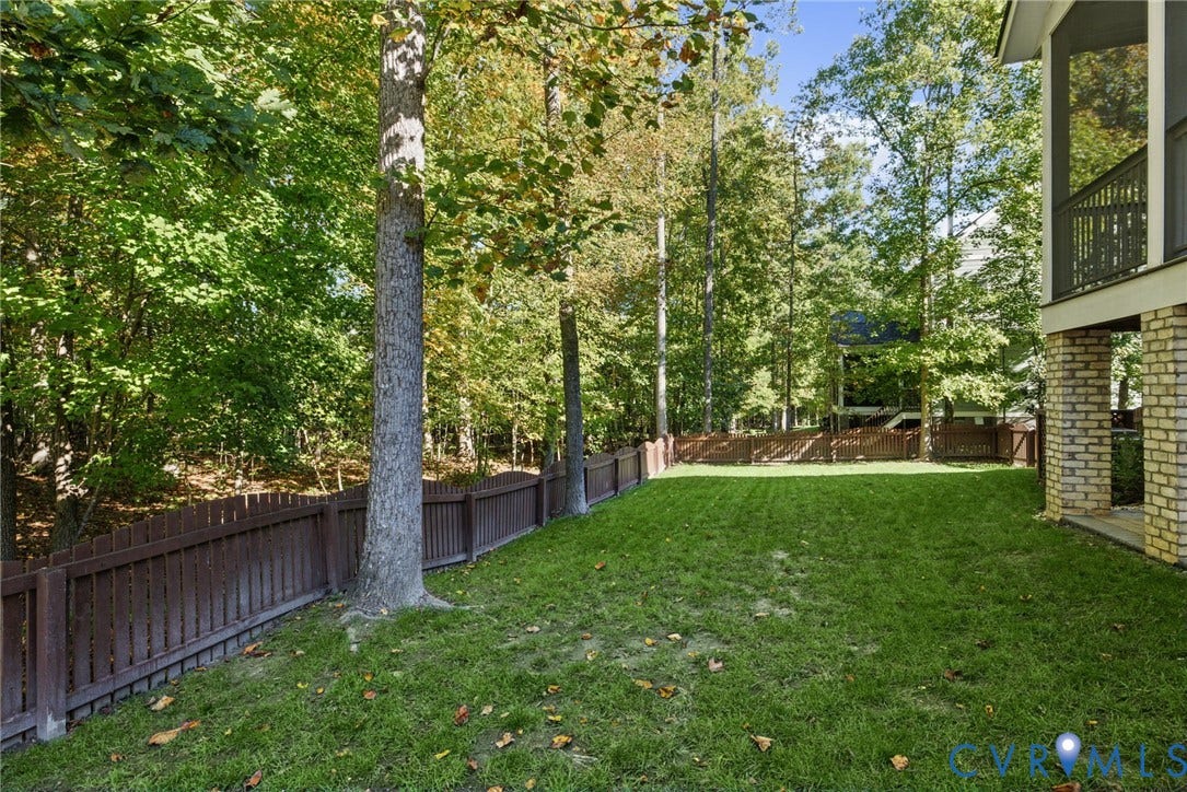 1425 Montcroft Way, Midlothian, VA 23112 Backyard featuring a fenced lawn, mature trees, and a covered porch with brick foundation pillars