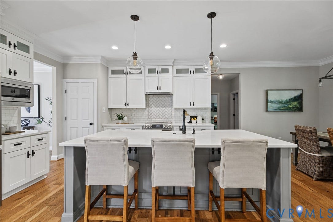 1425 Montcroft Way, Midlothian, VA 23112 Kitchen featuring a large central island with light-toned solid surface countertops, white shaker-style cabinetry, a herringbone-patterned tile backsplash, and dual glass globe pendant lights over the island