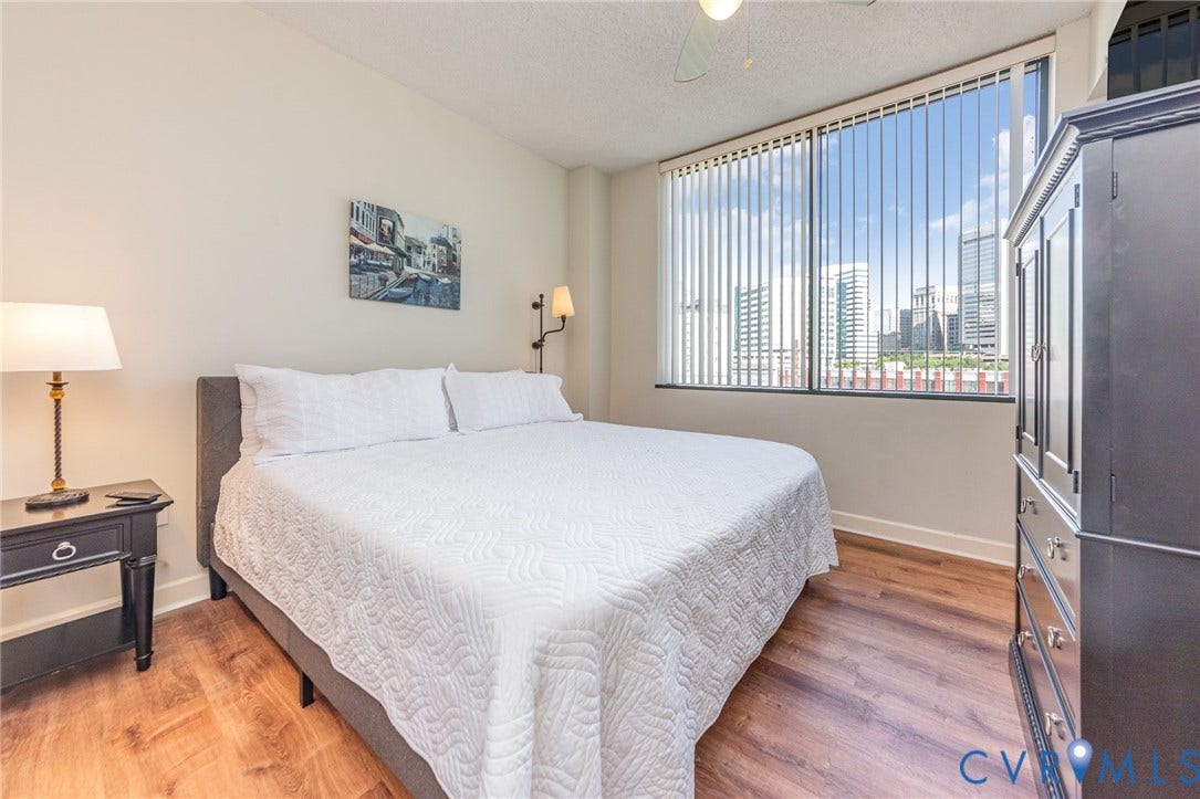 1101 Haxall Point, #709, Richmond, VA 23219 Wood-finish flooring, high ceilings, large window with vertical blinds, and a ceiling fan with light fixture