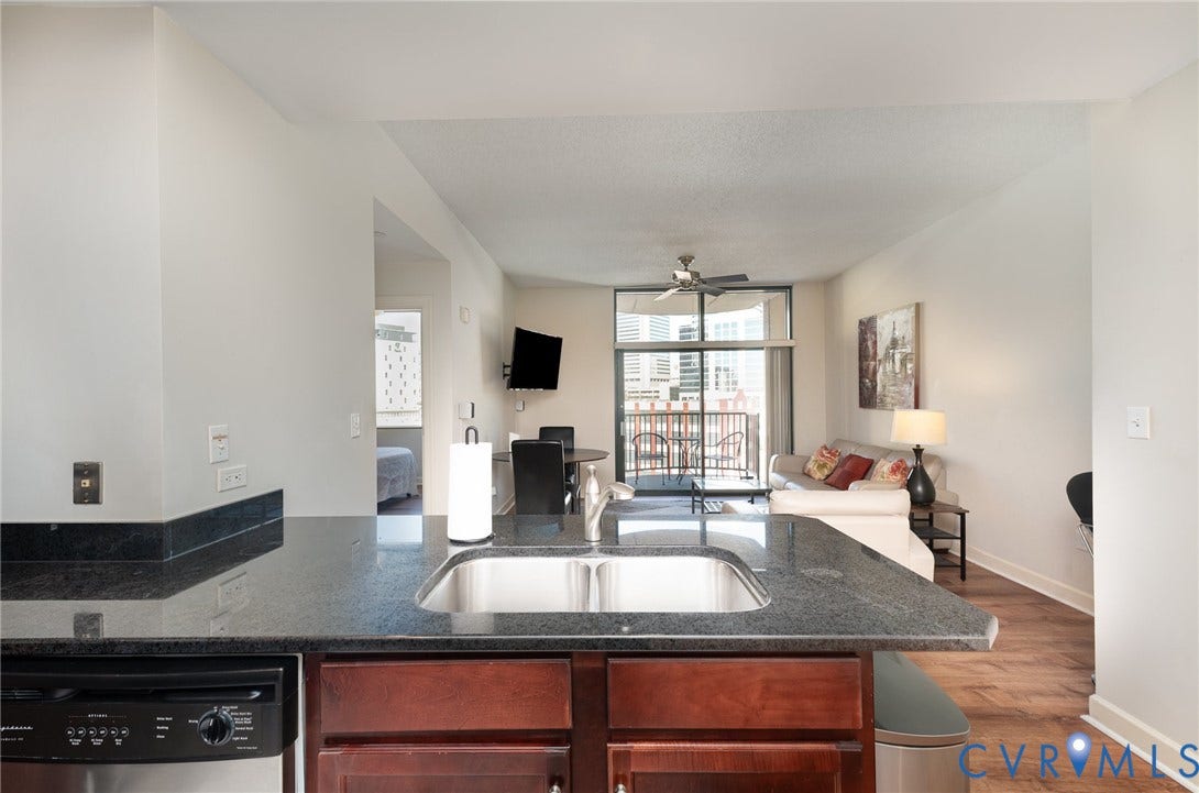 1101 Haxall Point, #709, Richmond, VA 23219 Kitchen featuring a stainless steel undermount sink, dark granite countertops, and wood-finish cabinetry