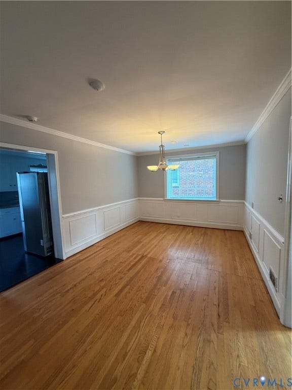 4612 Cutshaw Avenue, Richmond, VA 23230 Interior space featuring wood-finish flooring, white wainscoting, crown molding, and a central multi-light chandelier