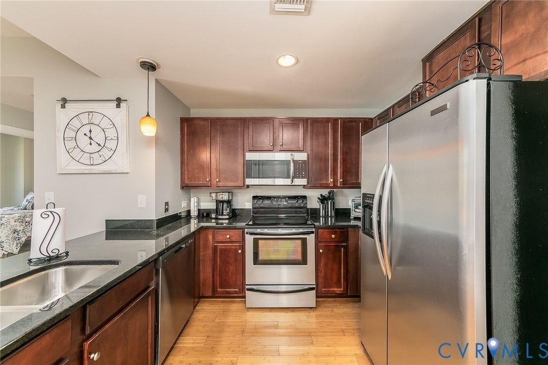 1101 Haxall Point, #511, Richmond, VA 23219 Kitchen featuring wood-finish flooring, stainless steel appliances, dark cabinetry, and dark countertops