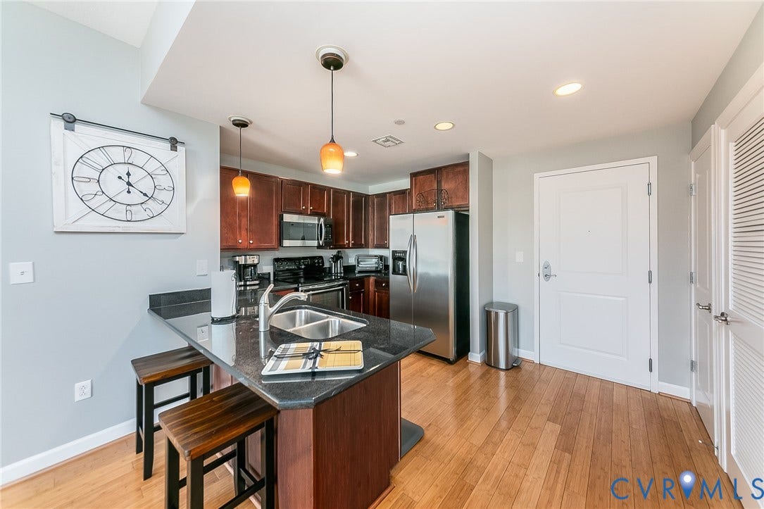 1101 Haxall Point, #511, Richmond, VA 23219 Kitchen with wood-finish flooring, dark cabinetry, and a dark stone countertop island