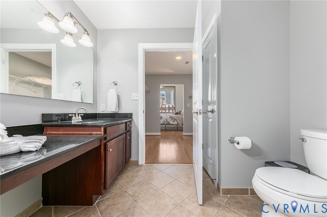 1101 Haxall Point, #511, Richmond, VA 23219 Bathroom featuring a dark wood-finish vanity with an integrated sink, a dark countertop, a wall-mounted mirror, and tile flooring