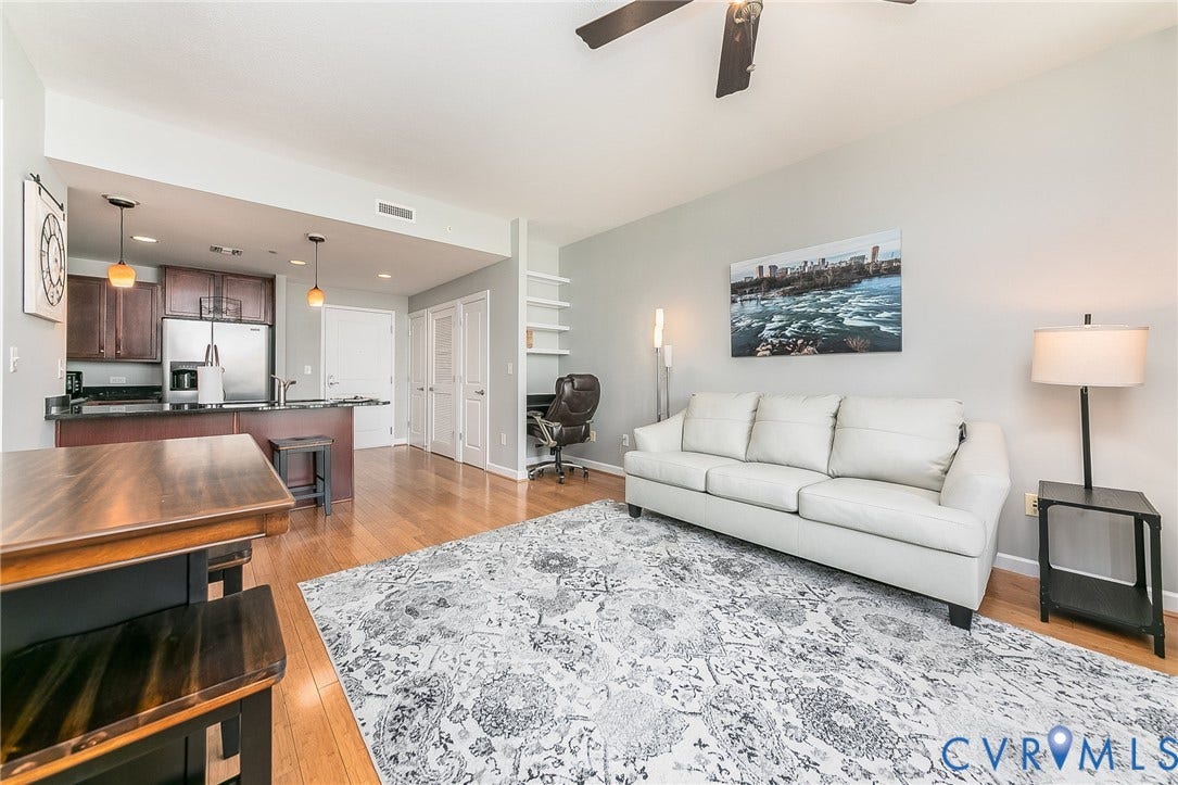 1101 Haxall Point, #511, Richmond, VA 23219 Open-concept living space with wood-finish flooring, a kitchen featuring wood cabinetry and stainless steel appliances, and built-in shelving