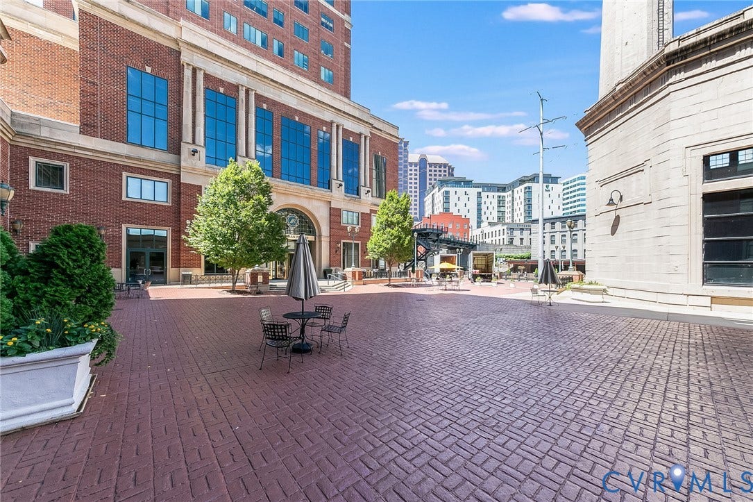 1101 Haxall Point, #511, Richmond, VA 23219 Expansive brick paver courtyard with mature trees, architectural building facades, and a modern light fixture