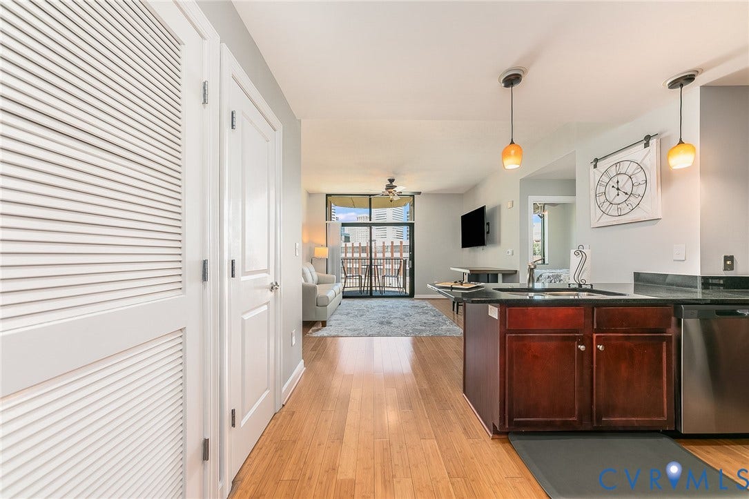 1101 Haxall Point, #511, Richmond, VA 23219 Wood-finish flooring throughout, kitchen island with dark cabinetry and sink, stainless steel dishwasher, and pendant lighting