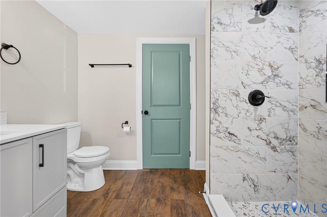 Walk-in shower with marble-style tiling and a pebble-finish floor