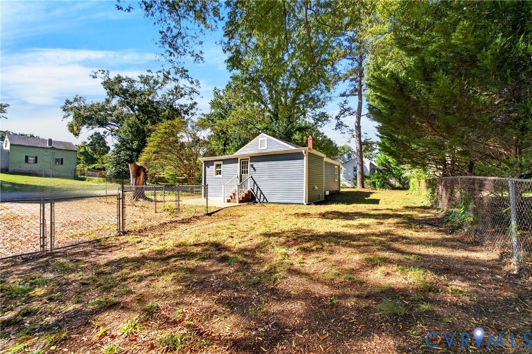 Chain link fence enclosing rear yard with mature trees
